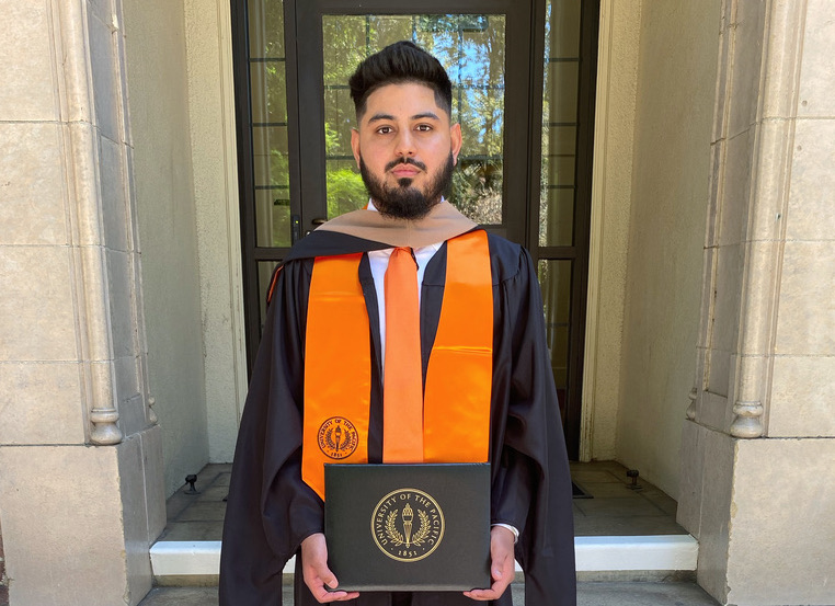 Pacific student Amreet Pannu holds diploma at University of the Pacific's campus.