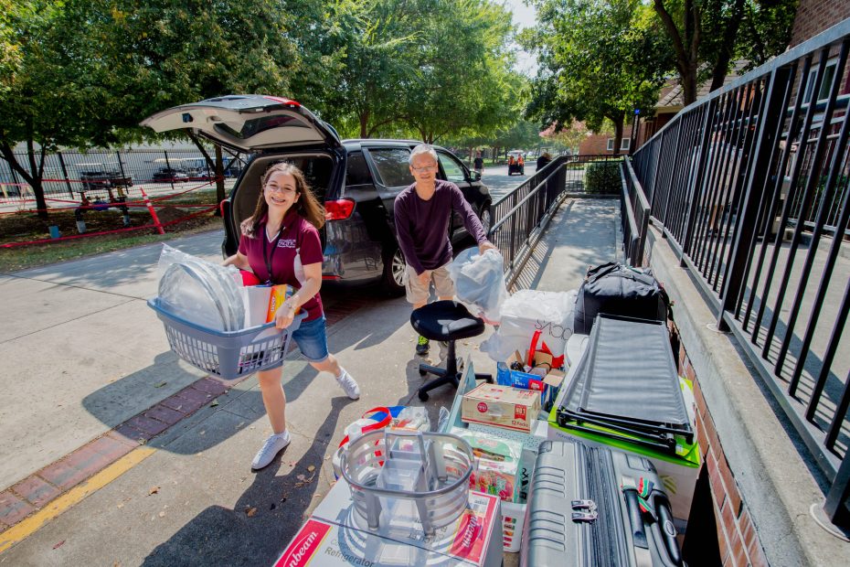Picture of two people moving things into a dorm.