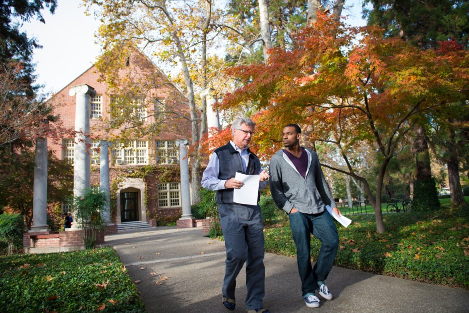 Student and professor speak while walking away from Knoles Hall.