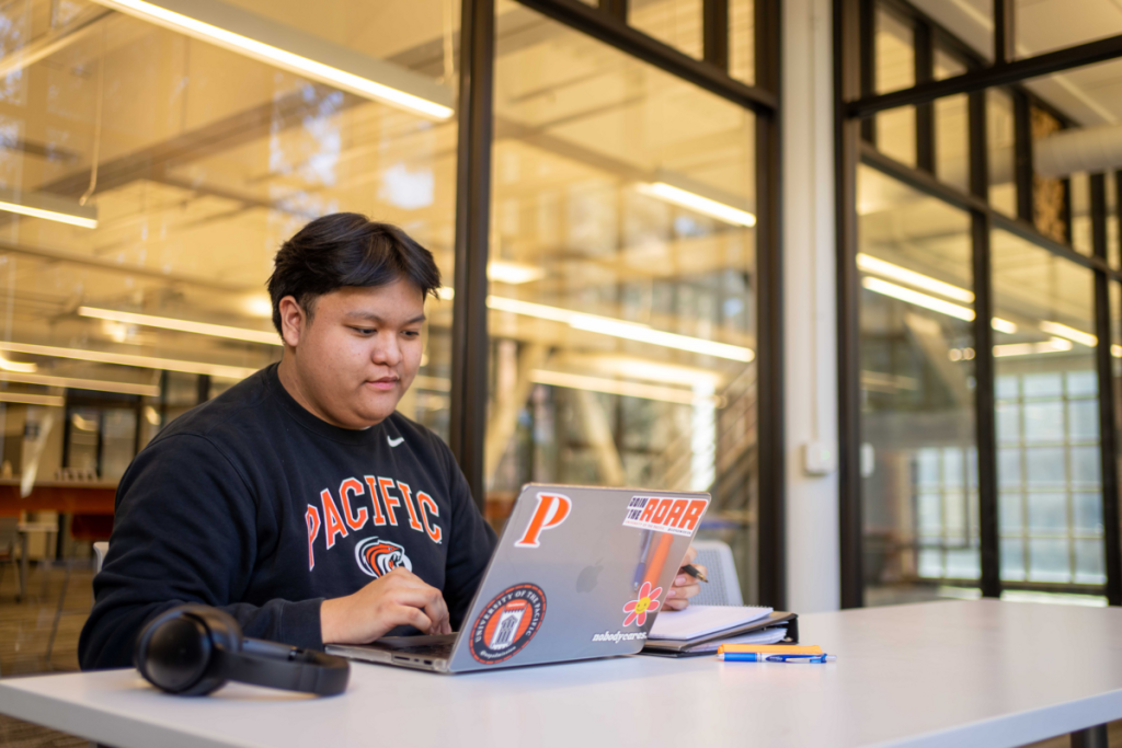 A student in the library is studying on his laptop.